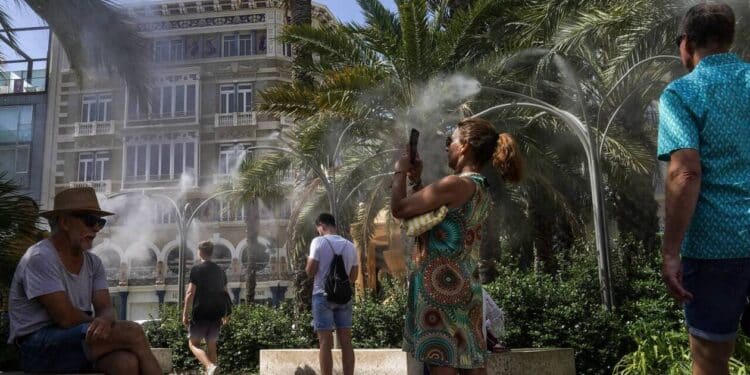 VALENCIA, SPAIN - JUNE 21: People take advantage of water mist fountains in a plaza as parts of Spain experience a heatwave on June 21, 2025 in Valencia, Spain. The country's national weather entry predicted that this summer is likely to be Spain's hottest on record, continuing the trend of the last three summers. (Photo by Michael Robinson Chávez/Getty Images) (Photo by GETTY IMAGES / GETTY IMAGES EUROPE / Getty Images via AFP)