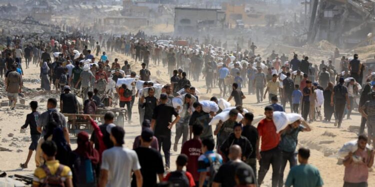 Palestinians gather as they carry aid supplies that entered Gaza through Israel, amid a hunger crisis, in Beit Lahia in the northern Gaza Strip July 20, 2025. REUTERS/Dawoud Abu Alkas      TPX IMAGES OF THE DAY