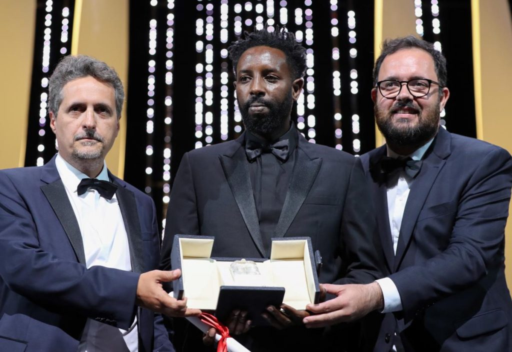Ladj Ly (au centre) reçoit le Prix du Jury pour Les Misérables, ex-aequo avec les brésiliens Juliano Dormelles et Kleber Mendonça pour Bacurau VALERY HACHE / AFP